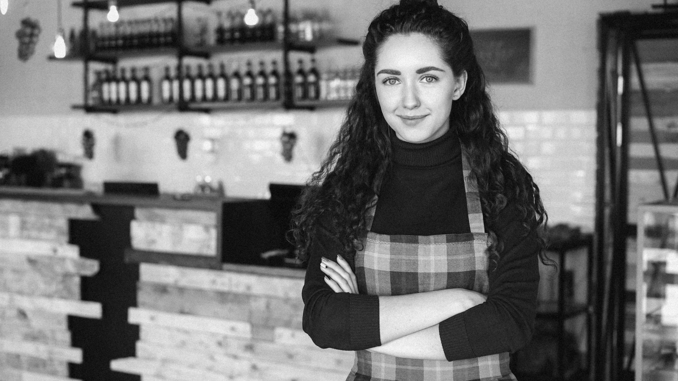 The owner of a coffee shop, arms crossed and smiling
